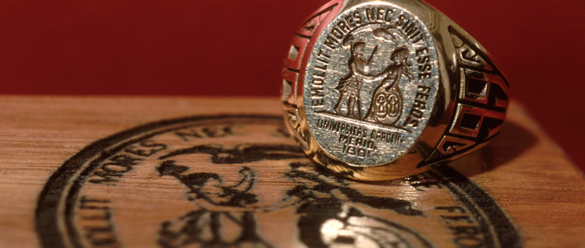 金色的UofSC戒指放在一张木桌上，上面有大学的印章