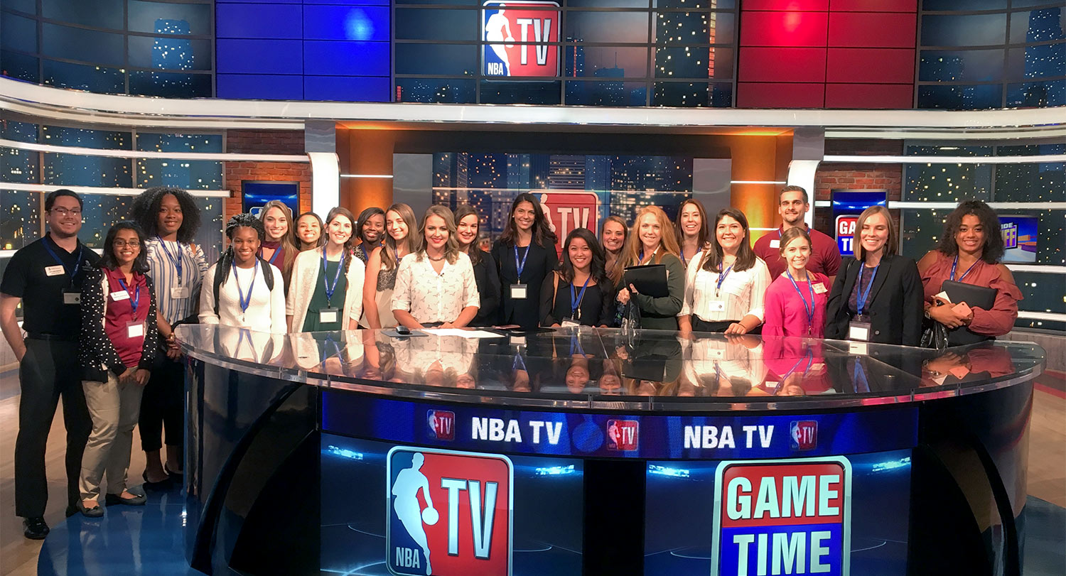 群学生站在新闻的办公桌在NBA的电视游戏的一天。