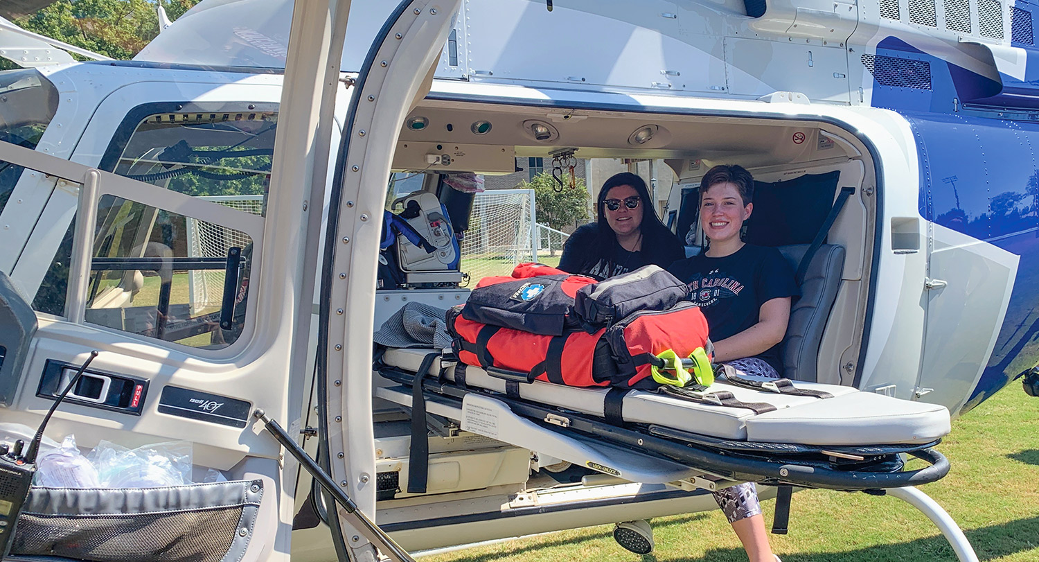 左拉简和另一个学生坐在一架直升机和空担架。