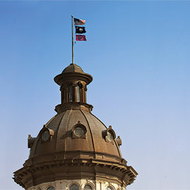 州议会大厦顶部的圆顶上悬挂着美国国旗、南卡州国旗和南卡州旗帜