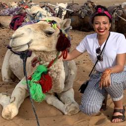 一个学生坐在骆驼旁边的图片